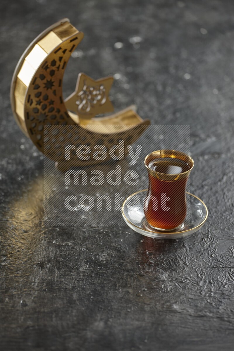 A wooden golden crescent lantern with different drinks, dates, nuts, prayer beads and quran on textured black background