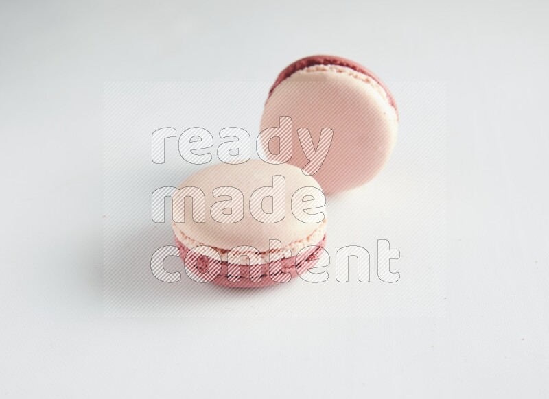 45º Shot of two Pink Litchi Raspberry macarons on white background