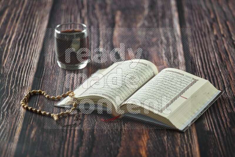 Quran with dates, prayer beads and different drinks all placed on wooden background