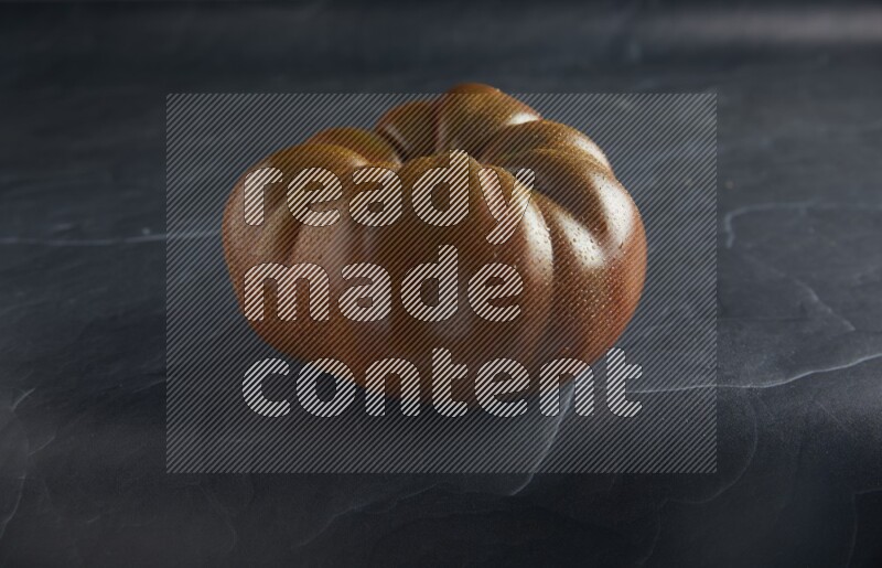 45 degree single heirloom tomato on a textured black slate background