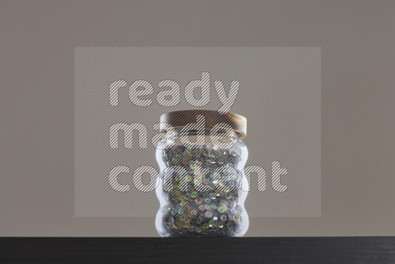 Sequins in a glass jar on black background
