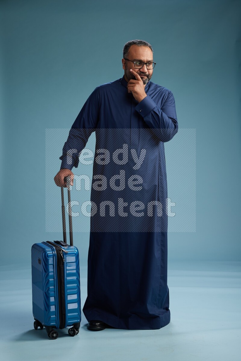Saudi Man without shimag Standing pulling travel bag on blue background