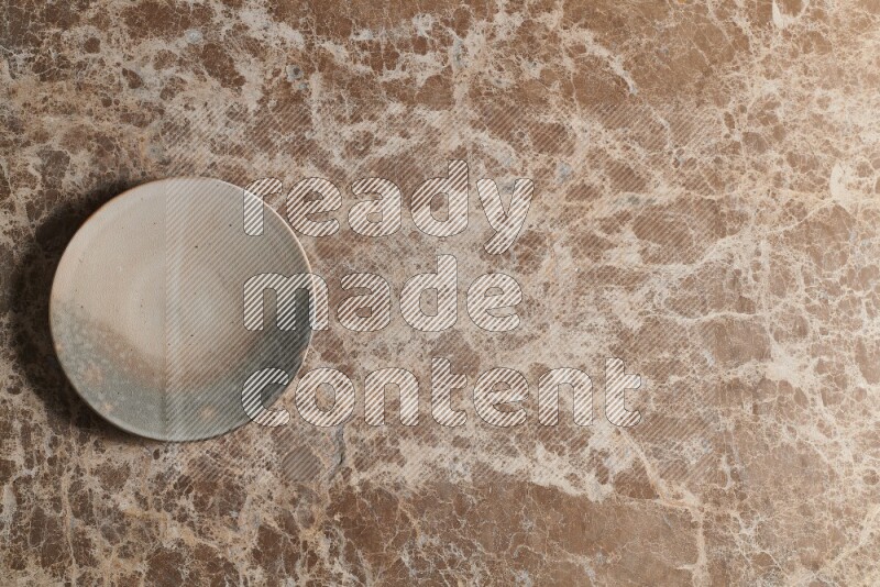 A multicolored pottery plate on beige marble background