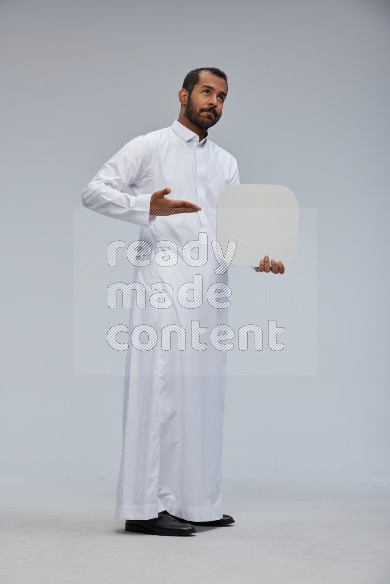 Saudi man wearing Thob standing holding social media sign on Gray background