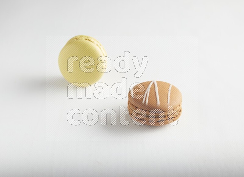 45º Shot of of two assorted Brown Irish Cream, and Yellow Lime macarons on white background