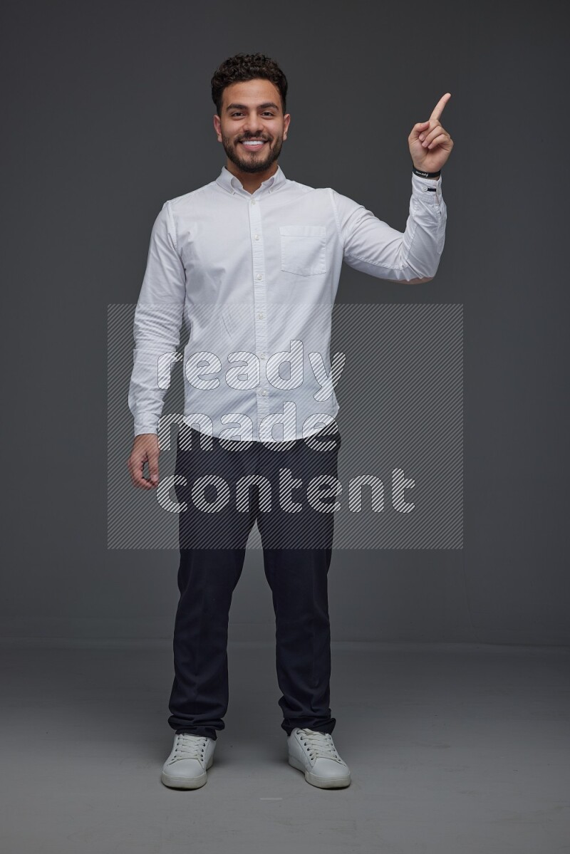 A man wearing smart casual standing and making multi hand gestures eye level on a gray background
