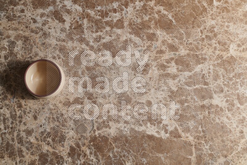 A beige pottery bowl on beige marble background