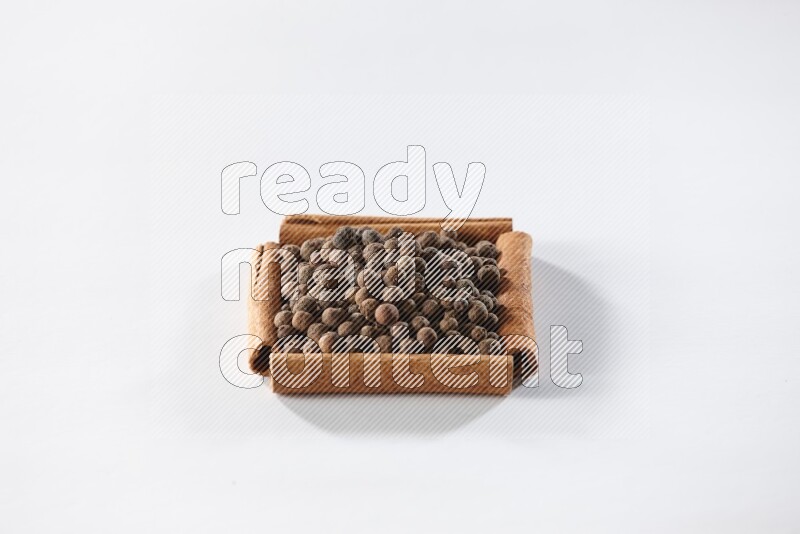 A single square of cinnamon sticks full of allspice on white flooring