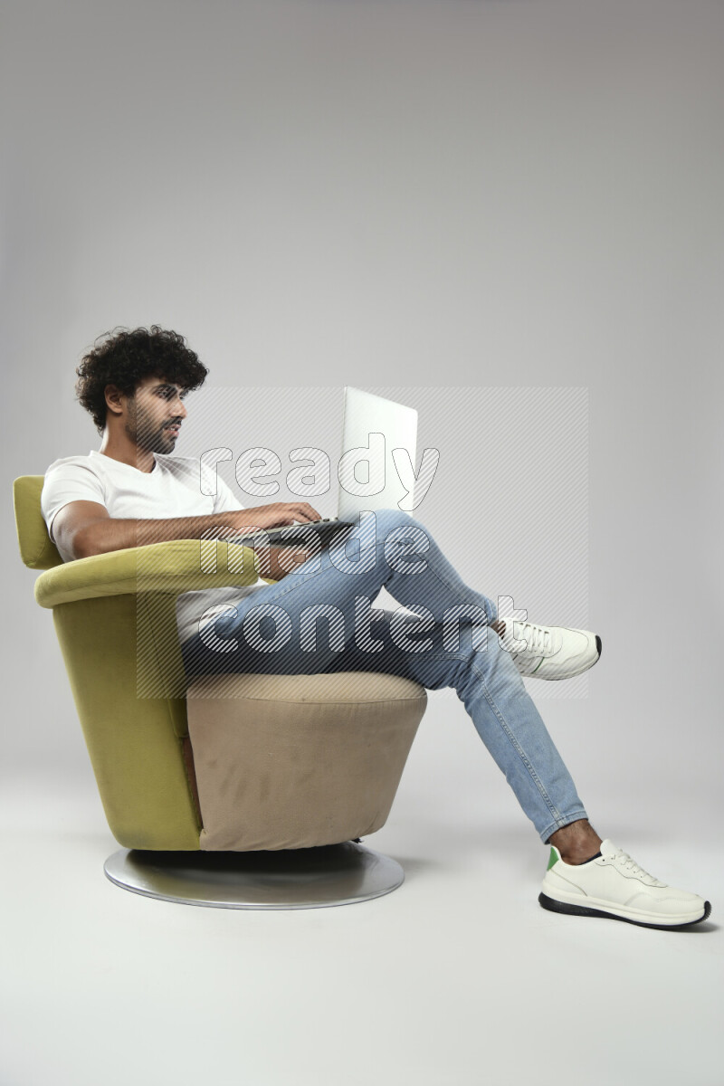 A man wearing casual sitting on a chair working on a laptop on white background