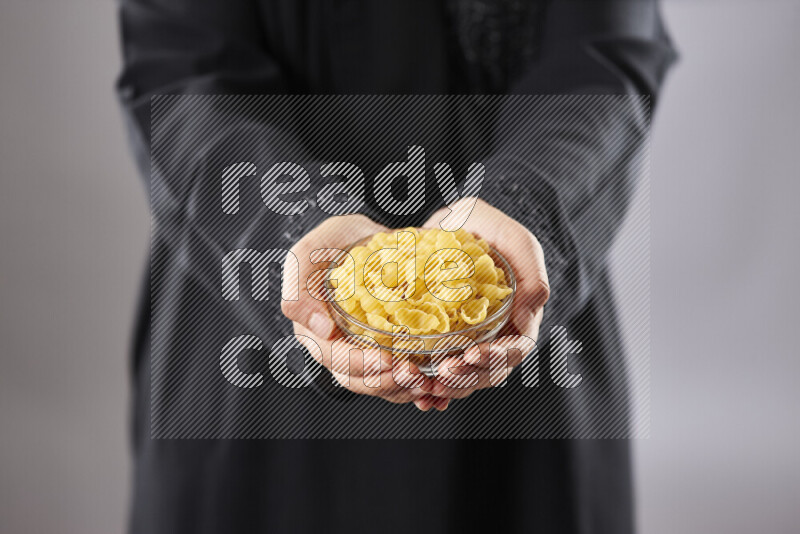 Woman in abaya holding different kinds of pasta in different positions