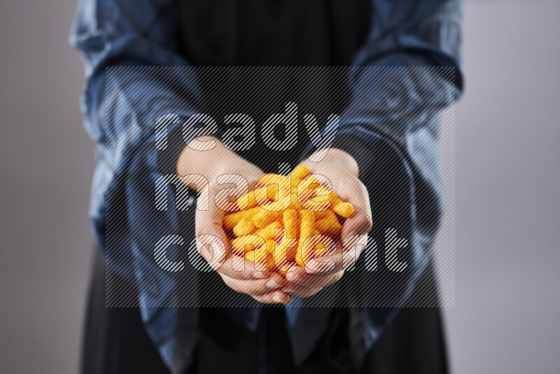 Woman in abaya holding different kinds of snacks in different positions