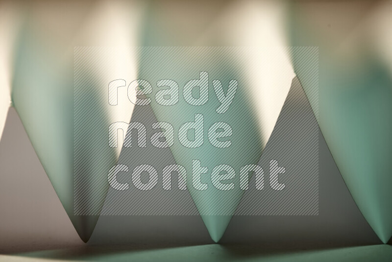 صورة مجردة مقربة تظهر طيات ورقية هندسية حادة بتدرجات اللون الأخضر مع درجات لونية دافئة