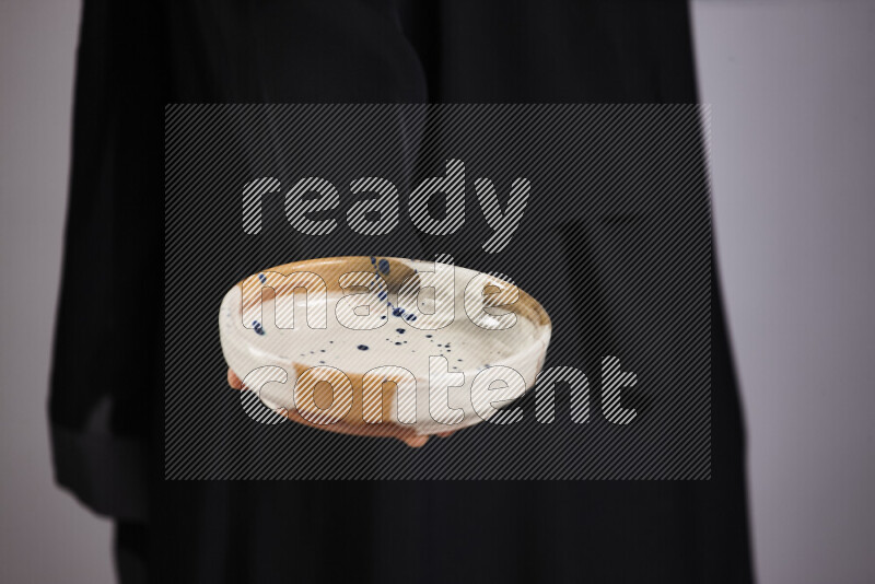 امرأة ترتدي عباءة سوداء تحمل أدوات فخارية مختلفة في أوضاع متعددة