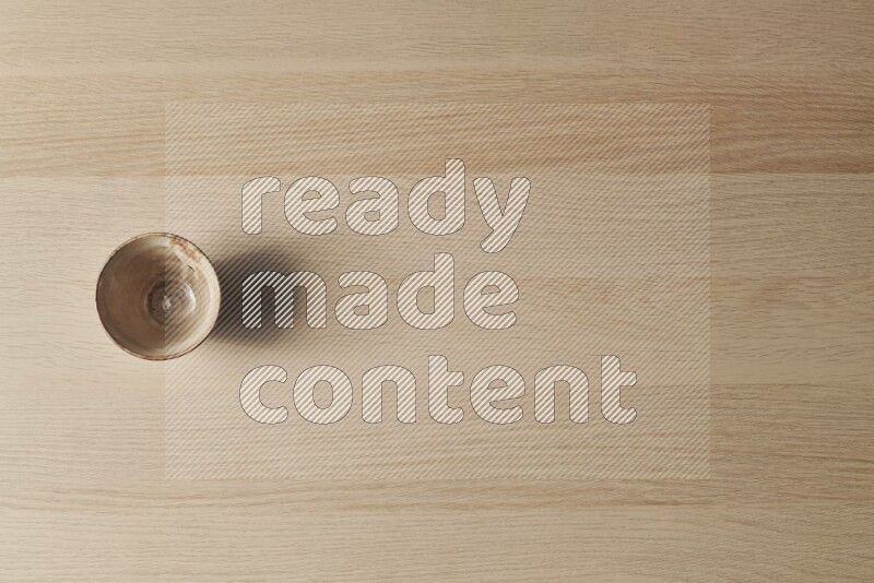 A beige pottery bowl on light wooden background