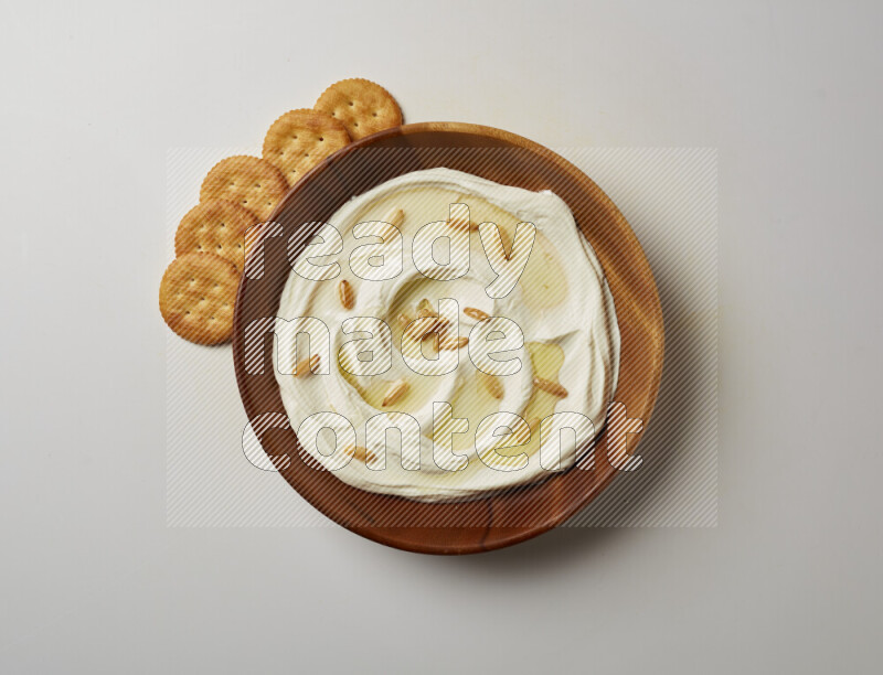 Lebnah garnished with pine nuts in a wooden plate on a white background