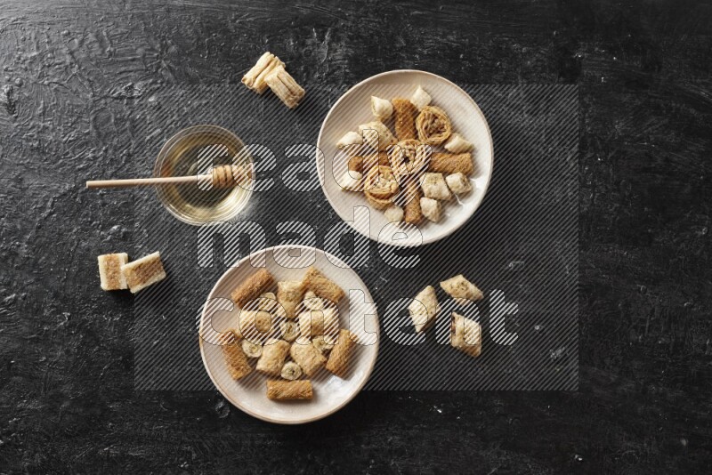 Oriental sweets in pottery plates with honey in a dark setup