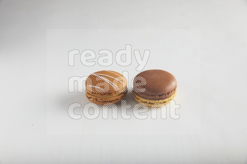 45º Shot of of two assorted Brown Irish Cream, and Yellow, and Brown Chai Latte macarons on white background