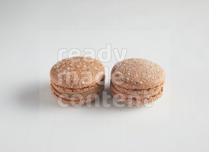 45º Shot of two Brown Hazelnuts macarons on white background
