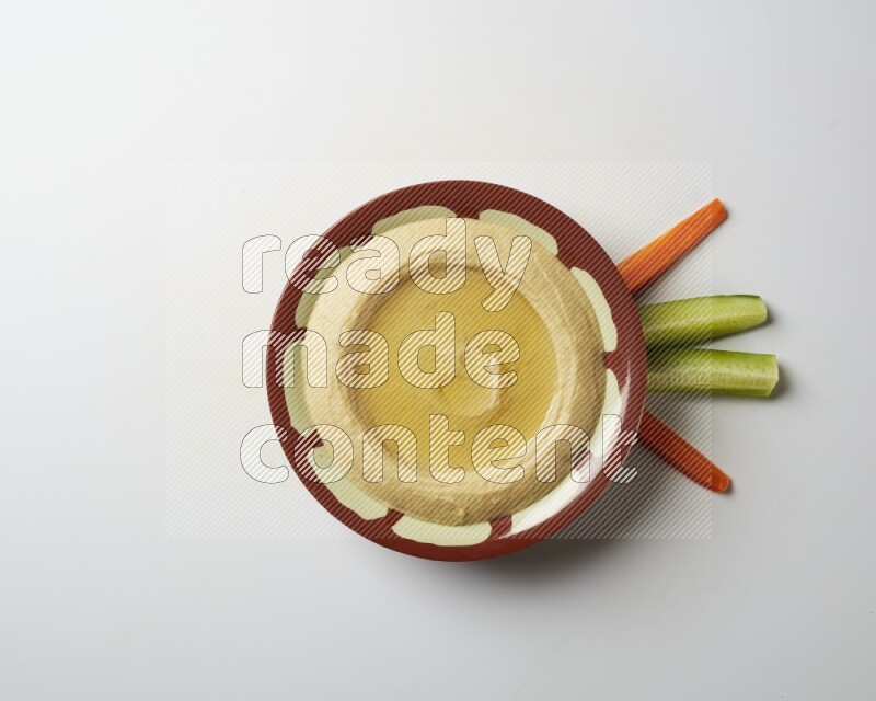 Hummus in a traditional plate garnished with olive oil on a white background