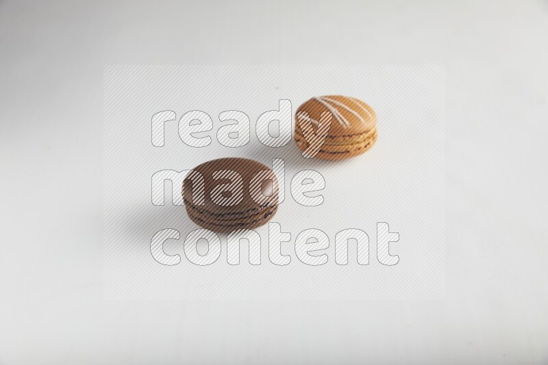 45º Shot of of two assorted Brown Irish Cream, and Brown Dark Chocolate macarons on white background