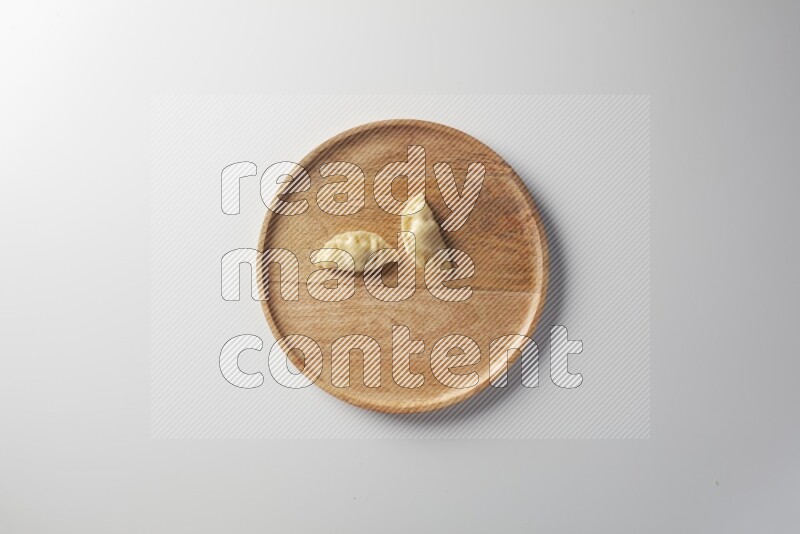 Two Sambosas on a wooden round plate on a white background