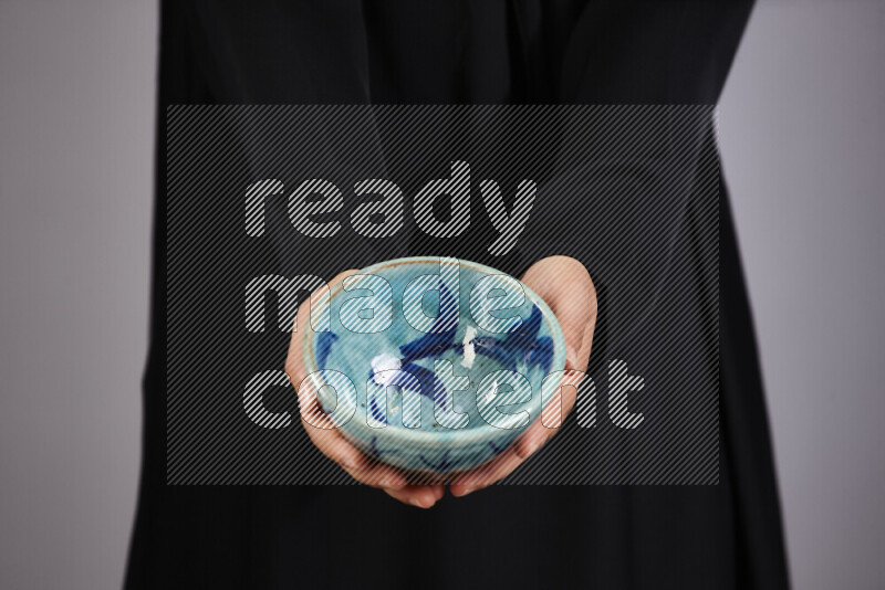 A woman in black abaya holding different pottery essentials in different positions