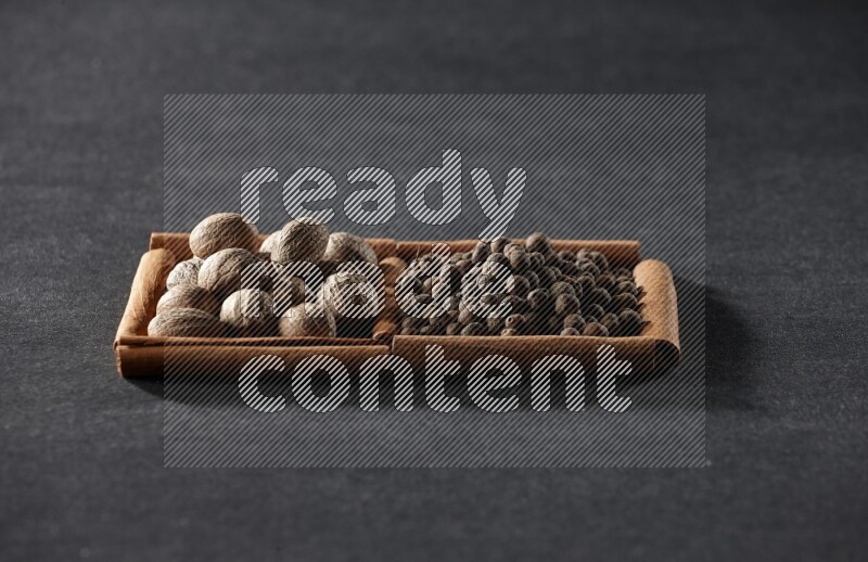 2 squares of cinnamon sticks full of nutmegs and allspice on black flooring