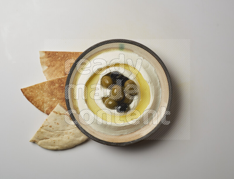 Lebnah garnished with whole black olives in a pottery plate on a white background