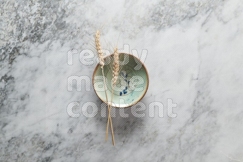 Wheat stalks on decorative pottery plate on grey marble background