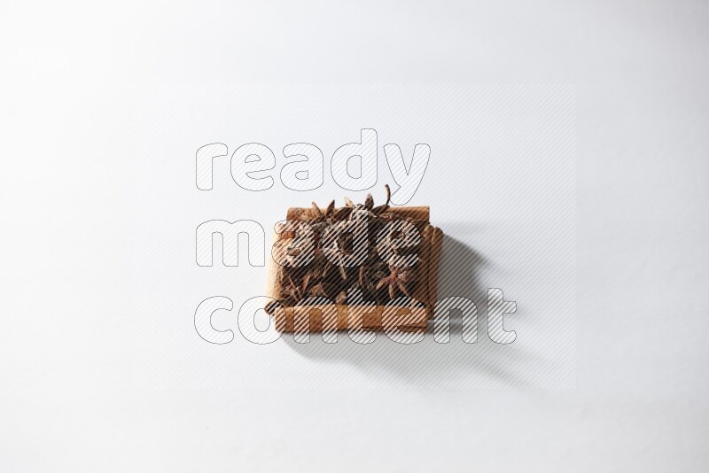 A single square of cinnamon sticks full of star anise on white flooring