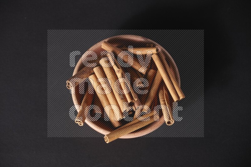 Cinnamon Sticks in a wooden bowl on black background