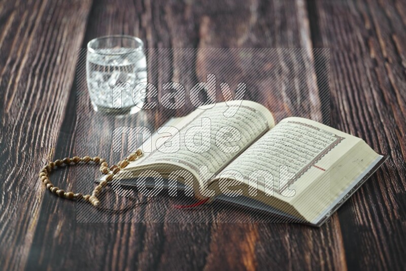 Quran with dates, prayer beads and different drinks all placed on wooden background