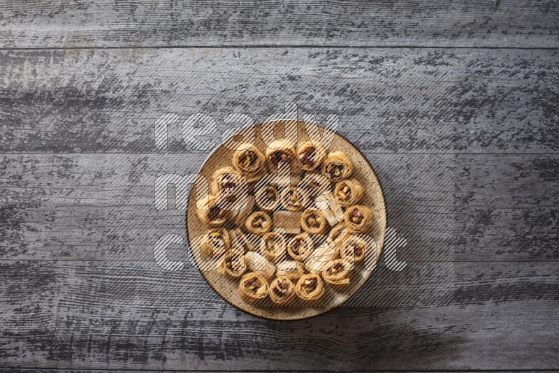 Oriental sweets in a pottery plate with nuts, coffee and honey in a dark setup