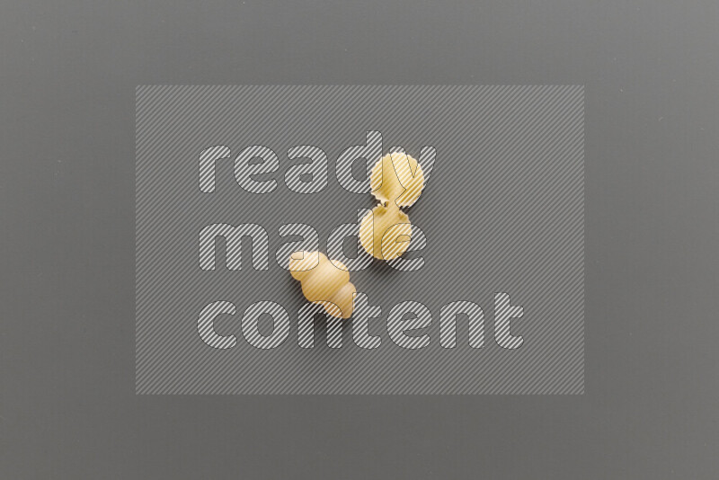 Snails pasta with other types of pasta on grey background