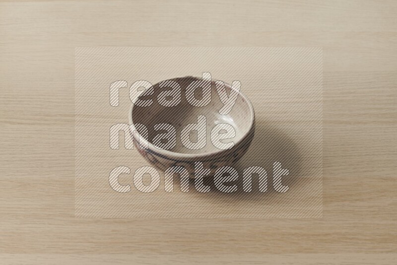 وعاء فخاري متعدد الألوان على خلفية خشبية فاتحة