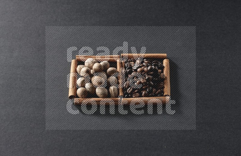 مربعان من أعواد القرفة ممتلئان بحبوب القهوة وجوزة الطيب علي خلفية سوداء