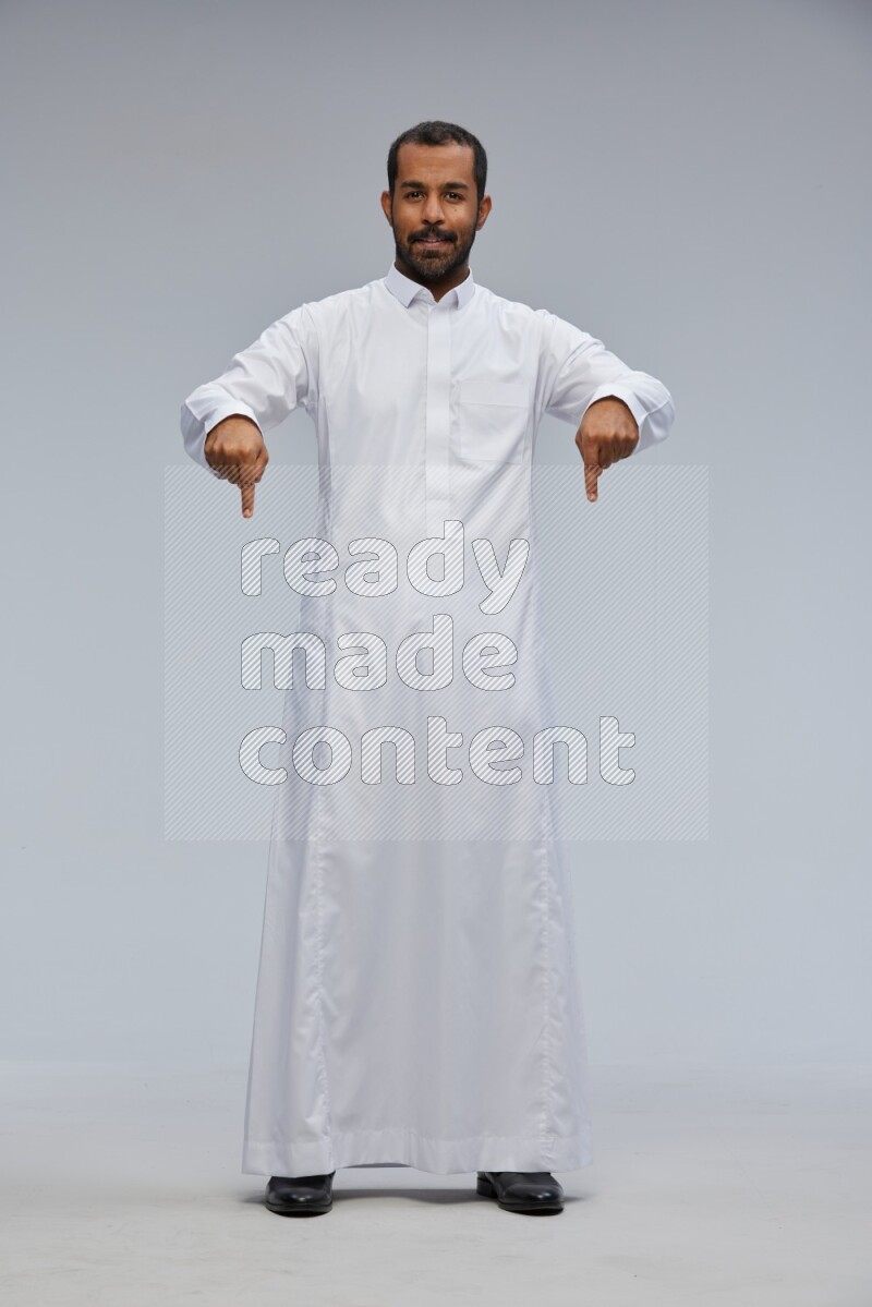 Saudi man Wearing Thob standing interacting with the camera on Gray background