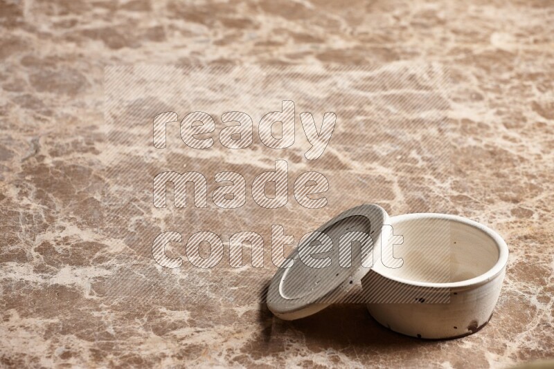 A white pottery bowl on beige marble background