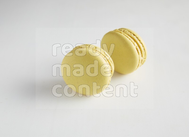 45º Shot of two Yellow Lime macarons on white background