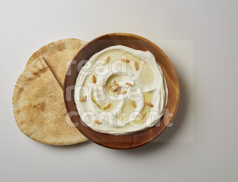 Lebnah garnished with pine nuts in a wooden plate on a white background