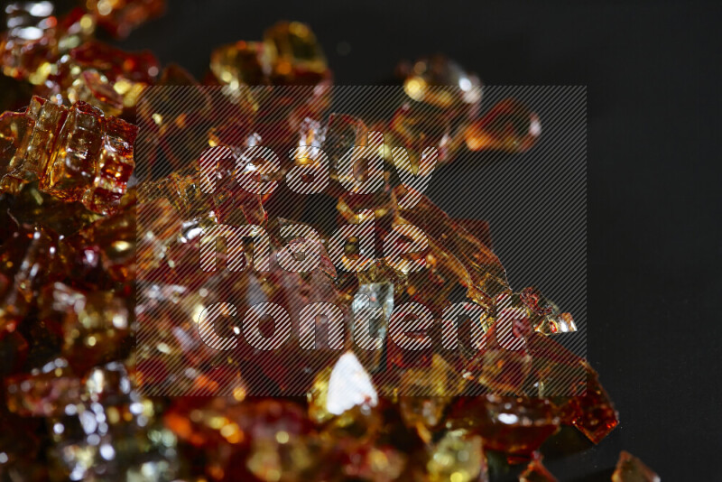 Transparent orange fragments of glass scattered on a black background