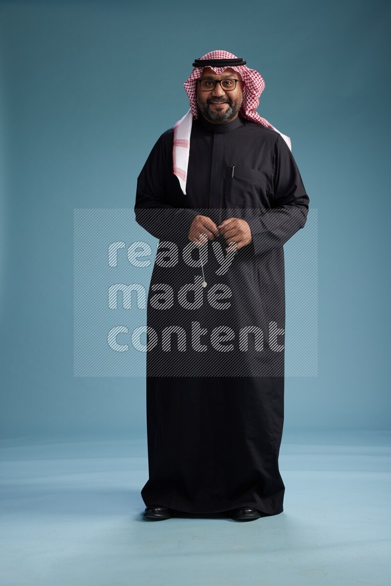 Saudi Man with shimag Standing Interacting with the camera on blue background