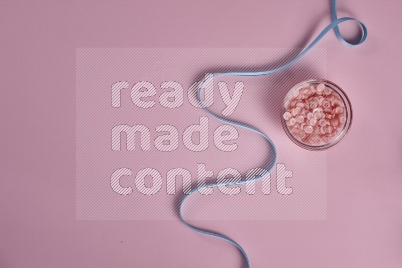 A blue collection of sewing and tailoring tools arranged on a pink background