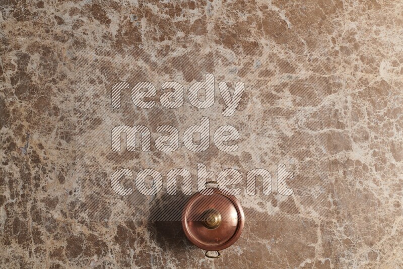 A small copper pot on beige marble background