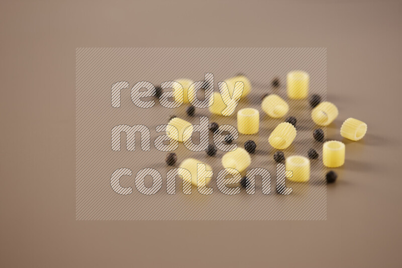 Raw pasta with different ingredients such as cherry tomatoes, garlic, onions, red chilis, black pepper, white pepper, bay laurel leaves, rosemary and cardamom on beige background