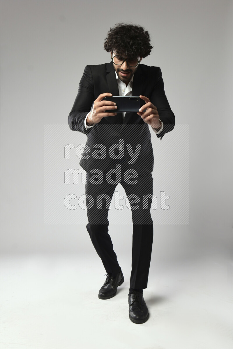 A man wearing formal standing and shooting with his phone on white background