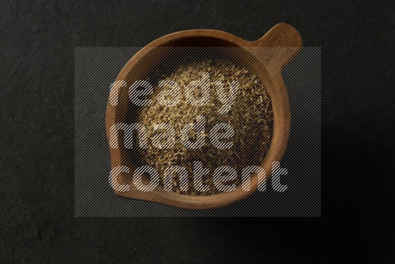 wooden round sauce bowl filled with herbs on grey textured countertop