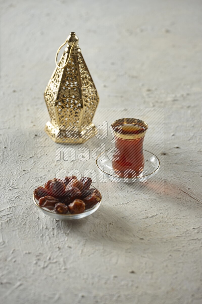 A golden lantern with different drinks, dates, nuts, prayer beads and quran on textured white background