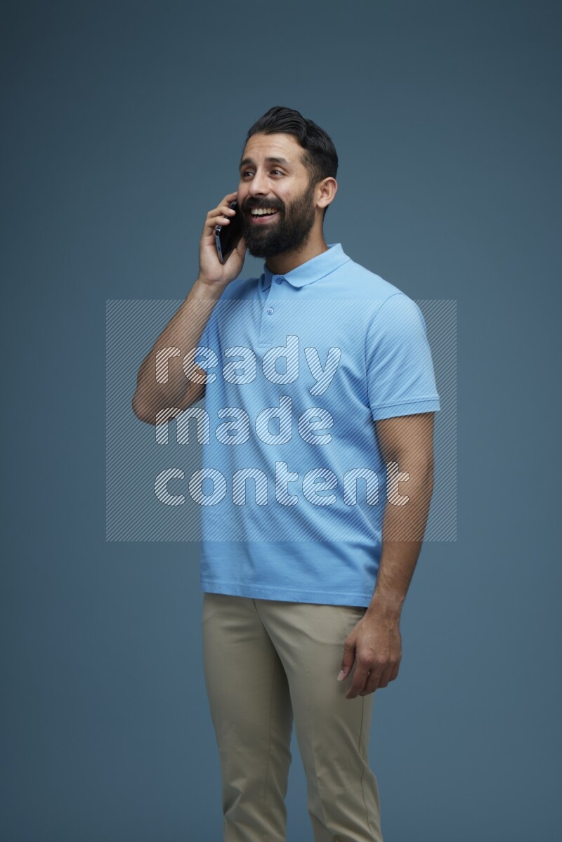 A man having a Call in a blue background wearing a Blue shirt