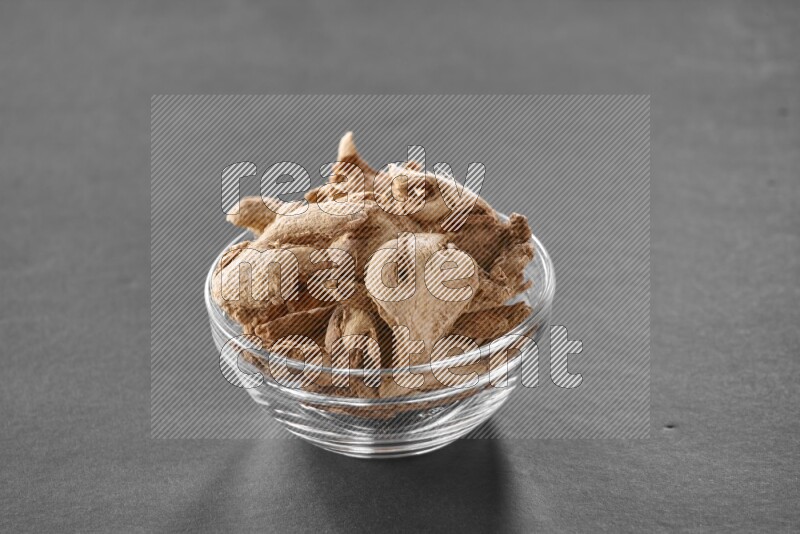 A glass bowl full of ginger on black flooring